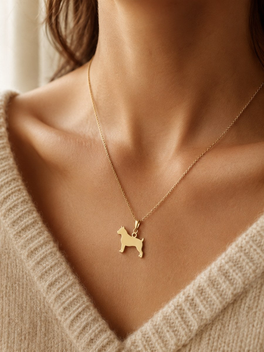 A gold dog-silhouette pendant worn on a cream knit