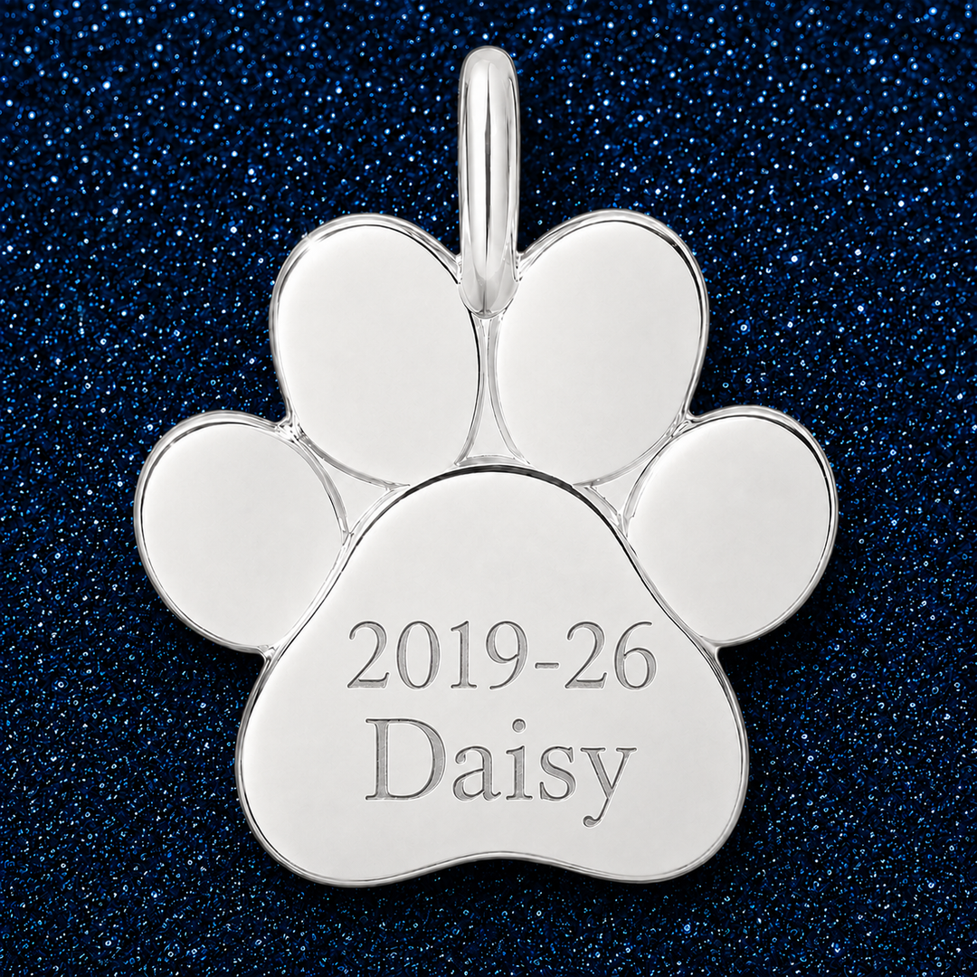 Silver paw charm engraved with memorial years and a pet name