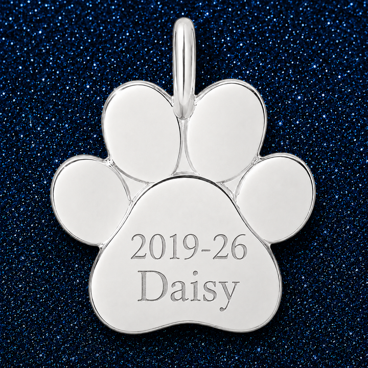 Silver paw charm engraved with memorial years and a pet name